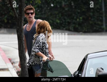 EXCLUSIVE!! Miley Cyrus and boyfriend Australian actor Liam Hemsworth take a ride around town in a convertible sports car driven by Liam before stopping at a center devoted to Meditation.  The lovey-dovey couple spent 30 minutes inside before walking out arm in arm and holding hands.  Miley, wearing jean shorts and a low cut top, tenderly kissed Liam's arm before getting back into the car and zooming off on the day of the Teen Choice awards.  Los Angeles, CA 7th August 2011 Stock Photo