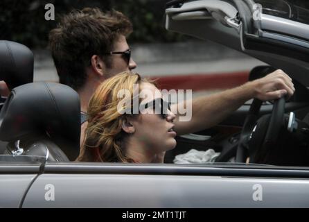 EXCLUSIVE!! Miley Cyrus and boyfriend Australian actor Liam Hemsworth take a ride around town in a convertible sports car driven by Liam before stopping at a center devoted to Meditation.  The lovey-dovey couple spent 30 minutes inside before walking out arm in arm and holding hands.  Miley, wearing jean shorts and a low cut top, tenderly kissed Liam's arm before getting back into the car and zooming off on the day of the Teen Choice awards.  Los Angeles, CA 7th August 2011 Stock Photo