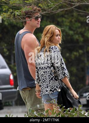 EXCLUSIVE!! Miley Cyrus and boyfriend Australian actor Liam Hemsworth take a ride around town in a convertible sports car driven by Liam before stopping at a center devoted to Meditation.  The lovey-dovey couple spent 30 minutes inside before walking out arm in arm and holding hands.  Miley, wearing jean shorts and a low cut top, tenderly kissed Liam's arm before getting back into the car and zooming off on the day of the Teen Choice awards.  Los Angeles, CA 7th August 2011 Stock Photo