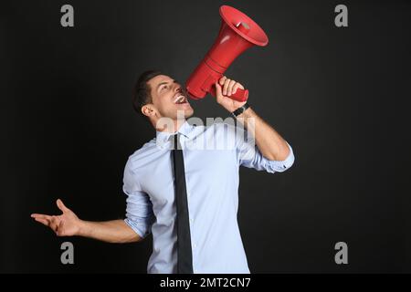 Handsome man with megaphone on black background Stock Photo