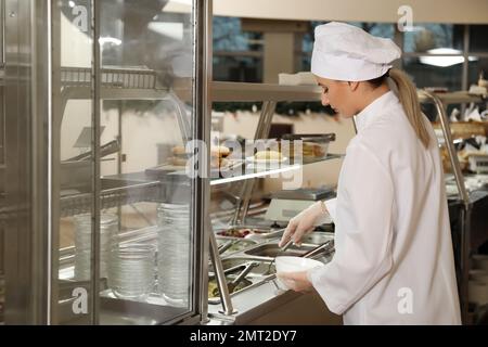 School canteen worker at serving line. Tasty food Stock Photo