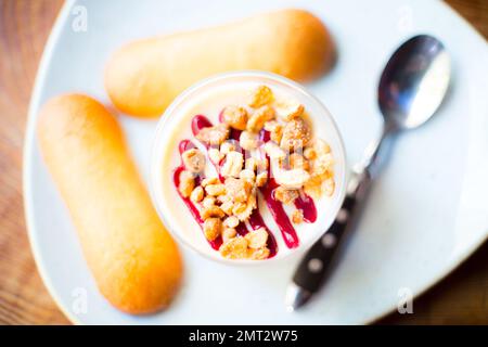 Cheesecake with red berries sauce served in a glass with different toppings. Stock Photo