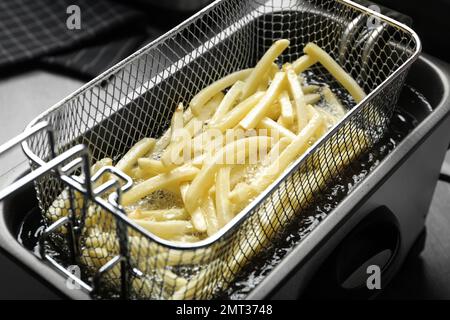 Cooking delicious french fries in hot oil, closeup Stock Photo