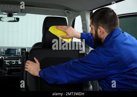 Young car wash worker cleaning automobile interior Stock Photo