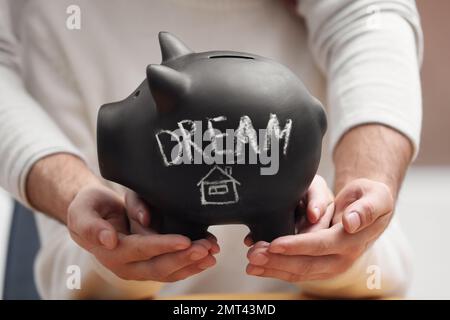 Couple holding piggy bank with word DREAM, closeup Stock Photo