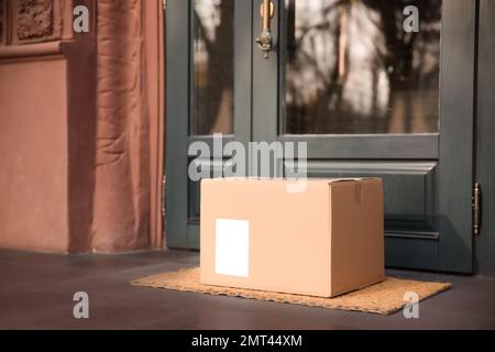 Delivered parcel on door mat near entrance Stock Photo