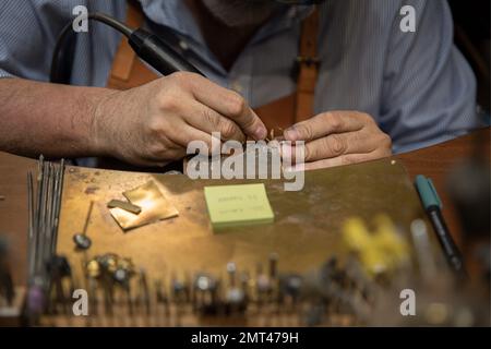 Silversmith working with tools on a jewelers bench in a traditional artisanal silversmith workshop and studio in Centro Storico in Florence, Italy Stock Photo