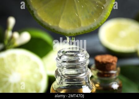 Citrus essential oil dripping from lime slice into bottle, closeup Stock Photo