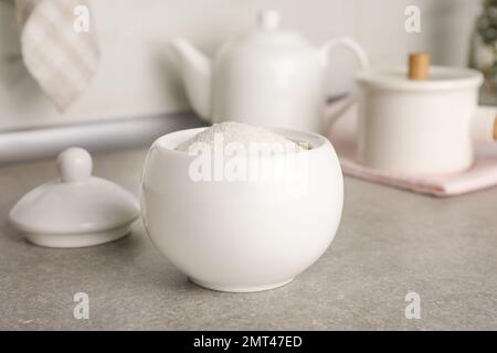 Ceramic bowl with white sugar on grey table Stock Photo