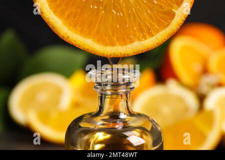 Citrus essential oil dripping from orange slice into bottle, closeup Stock Photo