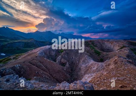 High alpine landscape with craters, mountains and ridges of the French Dauphiné Alps in the distance, seen from the pass Col du Galibier at sunset. Stock Photo