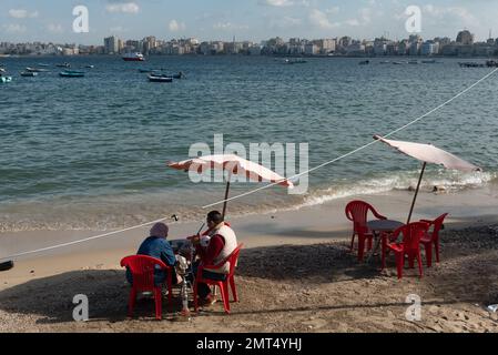 Alexandria, Egypt. December 1st 2022 An Egyptian couple sit on the receding Mediterranean beach of the Egyptian city of Alexandria in the northern Del Stock Photo