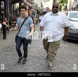 Nick Jonas of the American boy band Jonas Brothers casually strolls around Old Compton Street after leaving Queens Theatre in Soho. Nick, 17, made his West End theatre debut last night playing Marius in 'Les Miserables'.  While on his walk along the cobblestone street Nick was joined by his bodyguard. London, UK. 06/22/10. . Stock Photo