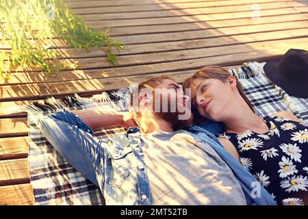Young and in love. an affectionate young couple lying on a blanket outdoors. Stock Photo
