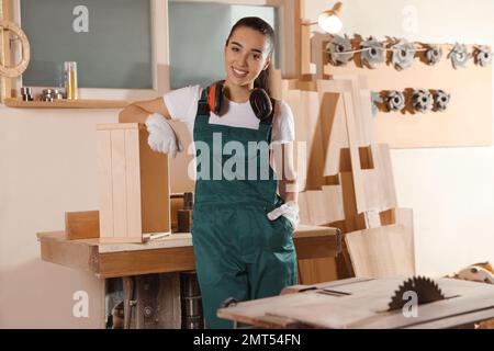 Professional female carpenter in uniform near workbench Stock Photo