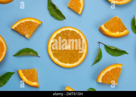 background with slides of orange and leaves on a blue background, trendy summer, fruity background. Stock Photo