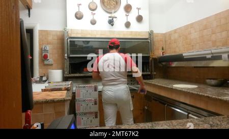 Pizza maker in a pizzeria in front of the oven Stock Photo