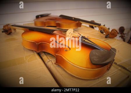 Violin in repair, on cardboard box Stock Photo