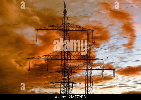 high voltage pylons for electricity and power against sky with dramatic clouds Stock Photo