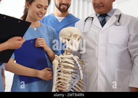 Professional orthopedist with human skeleton model teaching medical students in clinic Stock Photo