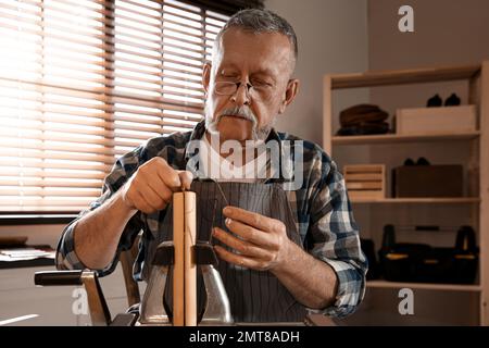 Man sewing piece of leather in workshop Stock Photo