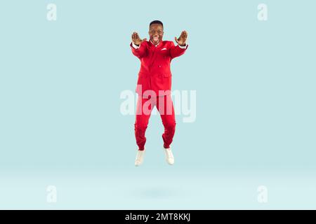 Funny stylish african american man having fun bouncing on pastel light blue background. Stock Photo