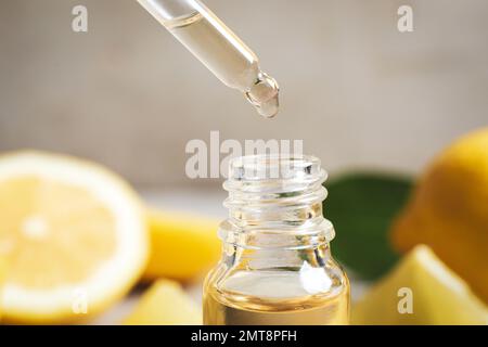 Citrus essential oil dripping from pipette into bottle, closeup Stock Photo