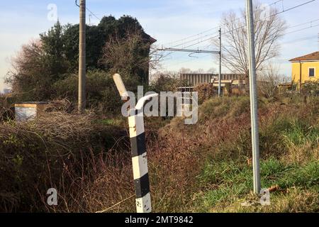 Abandoned  building covered by ivy by the edge of a railroad track on a cloudy day in the italian countryside Stock Photo