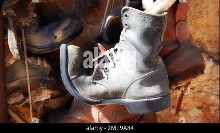 Flea market. Old boots hanging on a wall. Sunny weather. Retro shoes. Outdoor Stock Photo