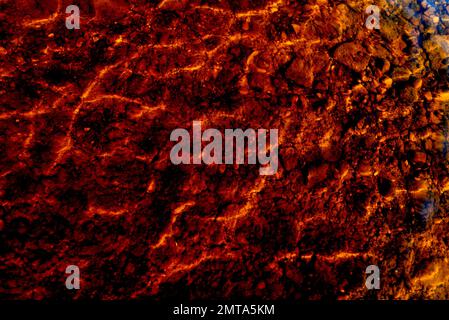 Abstract, natural background. Photo of a transparent surface of the water and with stones on the sandy bottom and the reflection of the light Stock Photo