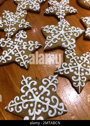 A vertical shot of decorated star-shaped cookies with white royal icing design on a wooden table Stock Photo