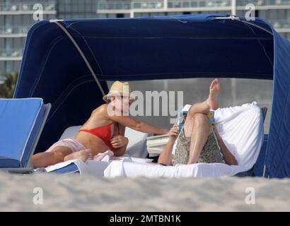 EXCLUSIVE!! 'America's Got Talent' judge Piers Morgan and his writer girlfriend Celia Walden chill out together on Miami Beach.  Morgan enjoyed some down time and seemed engrossed in Michael VaughanÕs autobiography, Time to Declare whilst his stunning girlfriend sunbathed in a red bikini.  Miami, FL 1/14/2010     . Stock Photo