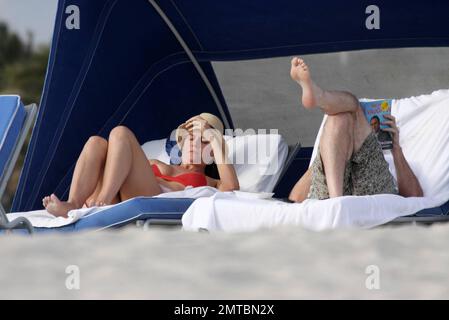 EXCLUSIVE!! 'America's Got Talent' judge Piers Morgan and his writer girlfriend Celia Walden chill out together on Miami Beach.  Morgan enjoyed some down time and seemed engrossed in Michael VaughanÕs autobiography, Time to Declare whilst his stunning girlfriend sunbathed in a red bikini.  Miami, FL 1/14/2010 Stock Photo