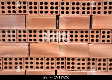 Background of baked clay bricks. Six-hole bricks stacked evenly. Construction materials. Stock Photo