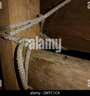A closeup shot of a spider web on an old wooden furniture tied with a rope Stock Photo