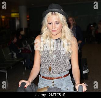 UK singer Pixie Lott shows off her tanned and slightly freckled face as she arrives at Heathrow from LA where she was working on a new album and also attending events including the 2011 Nickelodeon Kids' Choice Awards.  Wearing a trendy fedora with a feather in it, a patterned top paired with striped high-waist short shorts and brown lace-up shoes, Pixie looked happy to be home as she made her way through the airport pushing all her own luggage on a trolly. London, UK. 04/04/11. Stock Photo