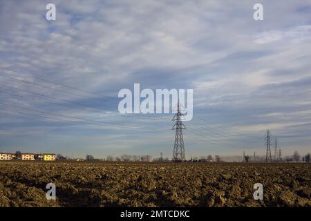 Rows  of electricity pylons and power lines over cultivated fields on a winter day in the italian countryside Stock Photo