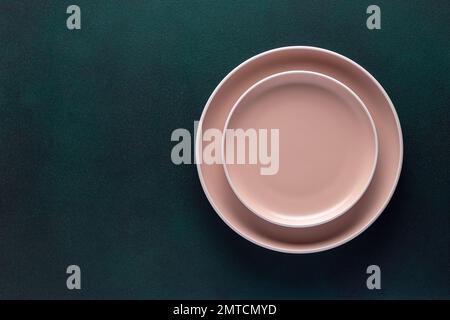 Empty beige plates on a dark green table, grunge background. Top view. Card or menu template, flat design. Tableware, crockery. Aerial view, copy spac Stock Photo
