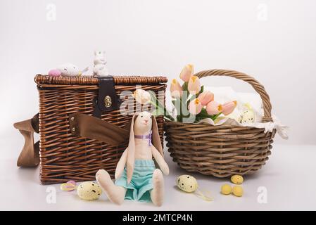 Vintage easter card, Happy holidays. Preparing for Easter picnic in nature. Two wicker baskets, bouquet of tulips, toy rabbit, sweets, Easter eggs and Stock Photo