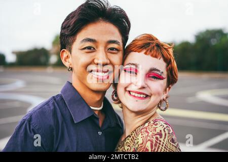 Young diverse friends having fun outdoor - Focus on gay asian guy wearing make-up Stock Photo