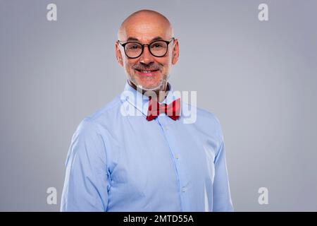 Close-up of mid aged man wearing shirt and bow tie and standing at isolated grey background. Copy space. Stock Photo