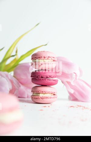 Stack of pink macaroons with pink tulips on white background Stock Photo