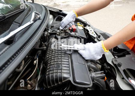 Woman car technician in uniform checking the car engine on the road Stock Photo