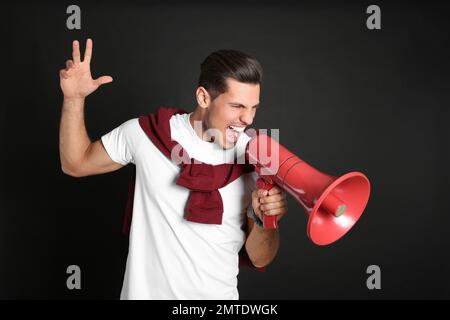 Handsome man with megaphone on black background Stock Photo