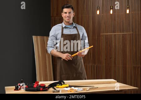 Handsome carpenter with folding rule near wooden wall Stock Photo
