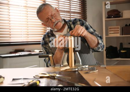 Man sewing piece of leather in workshop Stock Photo