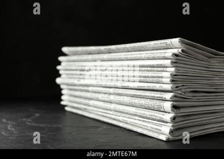 Stack of newspapers on dark stone table. Journalist's work Stock Photo