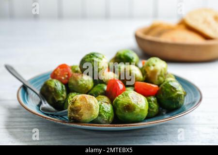 Roasted Brussels sprouts with cherry tomatoes on white wooden table Stock Photo