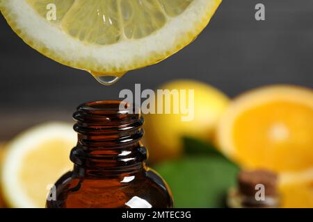 Citrus essential oil dripping from lemon slice into bottle, closeup Stock Photo