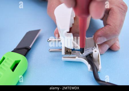 Dismountable electrical plug for an electric cord is assembled with screwdriver. Stock Photo